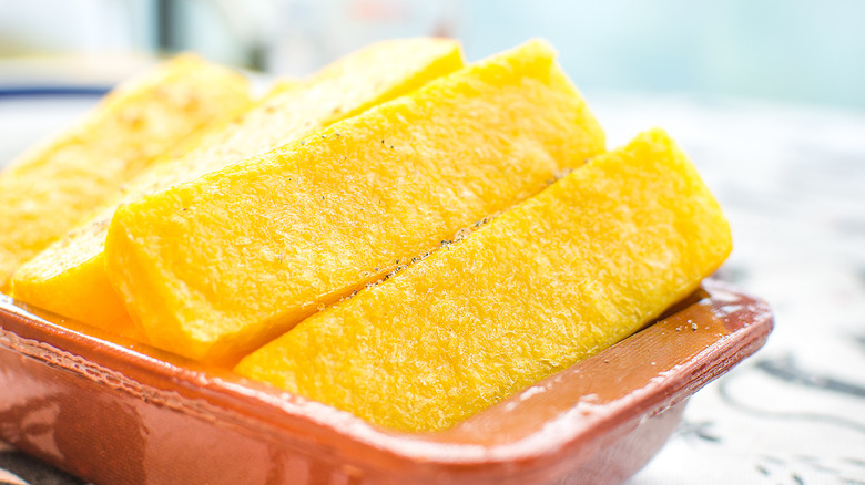 Places of fried cornmeal mush formed into sticks, in a dish