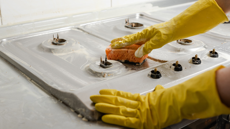 Gloved hands cleaning stove