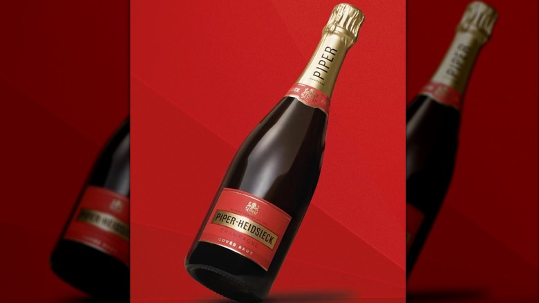 A bottle of Piep-Heidsieck champagne with its iconic red label in front of a red background