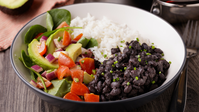 A bowl of rice, black beans, and assorted vegetables