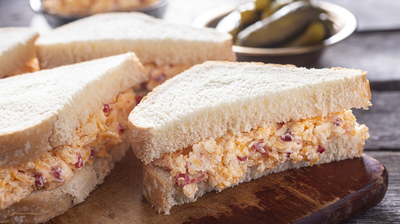 Sliced pimento cheese sandwiches rest on a chopping board