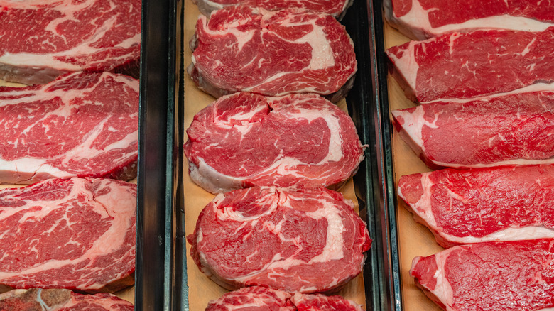 Row of raw steaks in case.