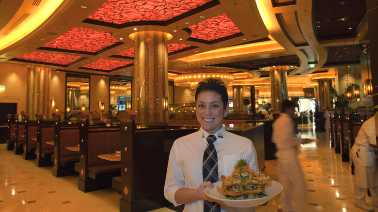 A Cheesecake Factory server presents a multi-tiered dish.