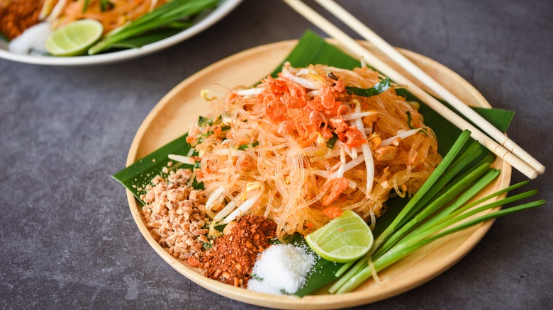 Pad Thai on a plate with lemongrass, crushed peanuts and lime slices