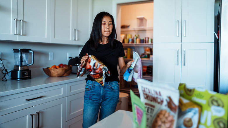 A woman organizes snacks for her pantry.