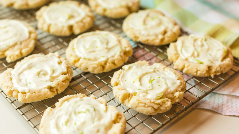 Cookies with lime icings on a metal cooling rack with patterned towels in the background.