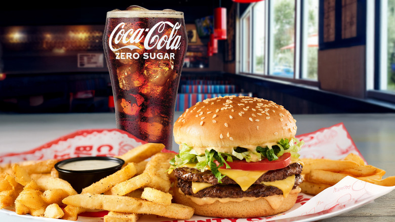 A Red Robin burger combo with a double cheeseburger and fries on paper, plus a Coke Zero in a glass behind them