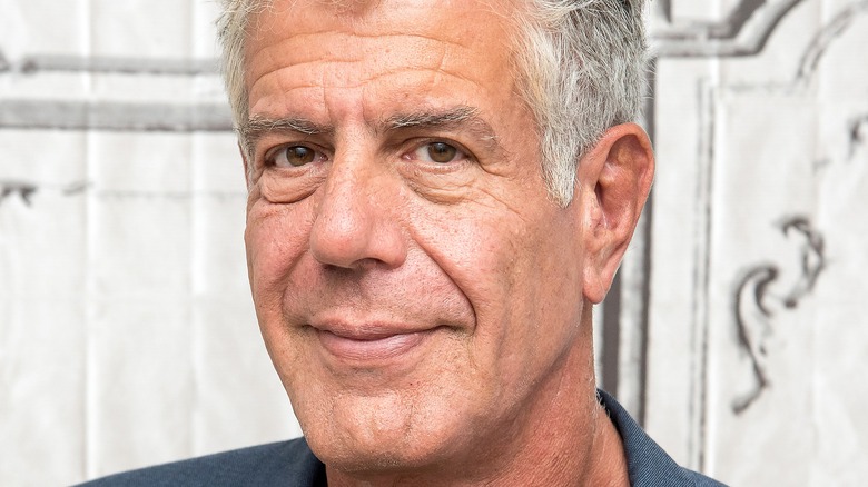 Anthony Bourdain smiling in front of building