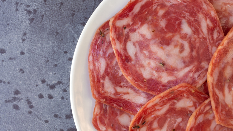 Top-view close up of sliced soppressata on a white plate