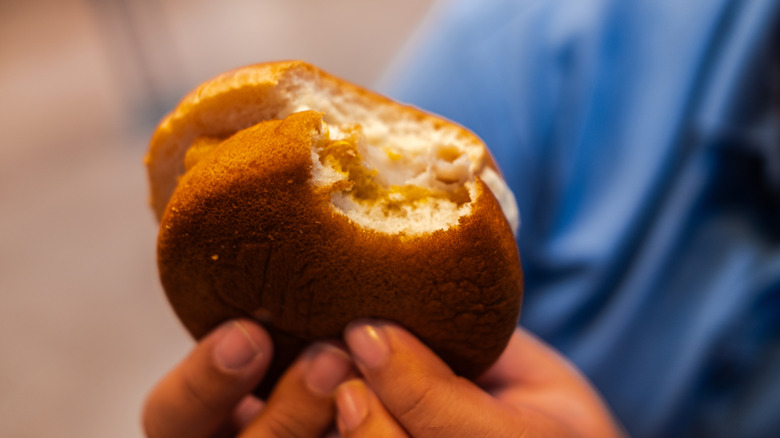 A person holds a filet-o-fish with a bite taken