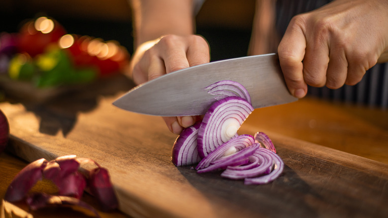 Person slicing a red onion