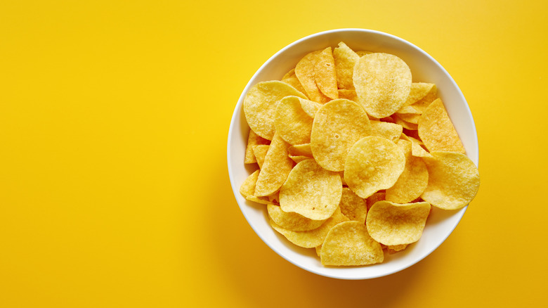potato chips in white bowl against yellow background