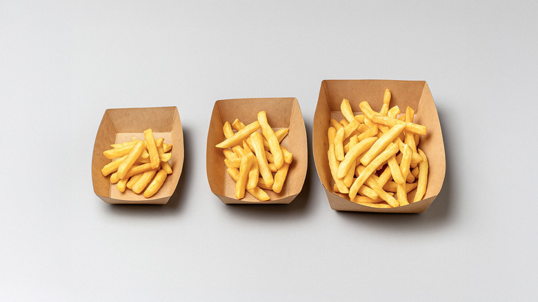 A small, medium, and large container of french fries on a gray background