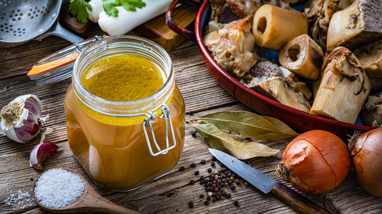 A jar of bone broth surrounded by its ingredients