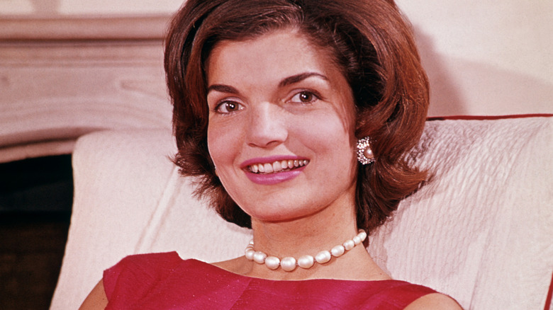 Jackie Kennedy smiles sitting on a couch