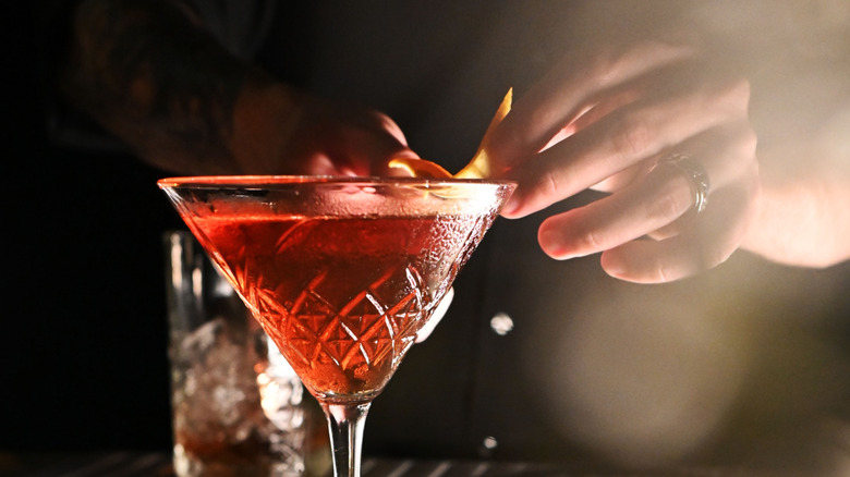 bartender garnishing drink in glass