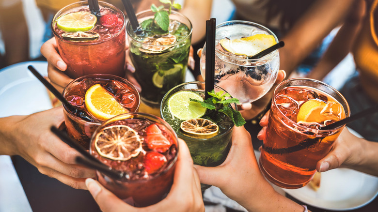 Hands clinking together various cocktails