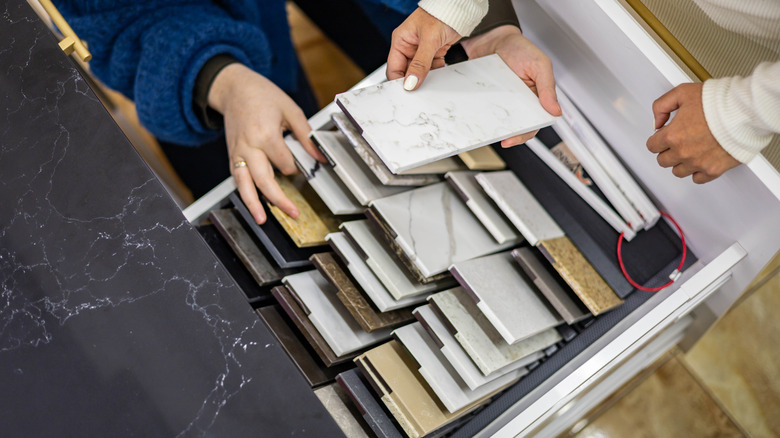Overhead view of people choosing marble countertop colors from a pallette