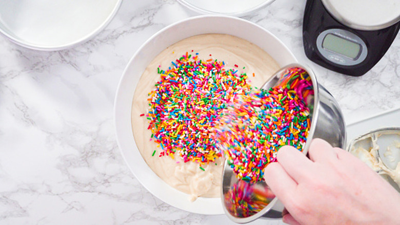 Person mixing sprinkles into cake mix