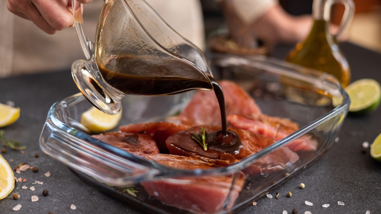 Someone pouring soy sauce on sliced tuna to marinate
