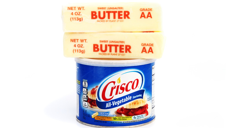 Tub of Crisco with two sticks of butter balanced on top
