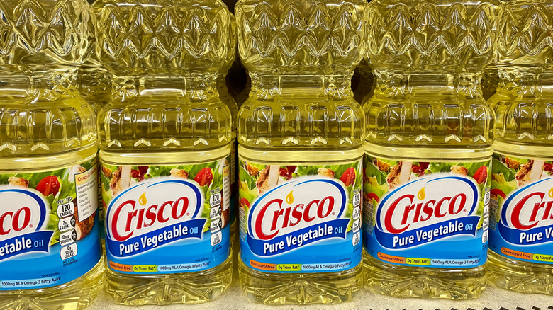 Bottles of Crisco vegetable oil lined up on grocery store shelf