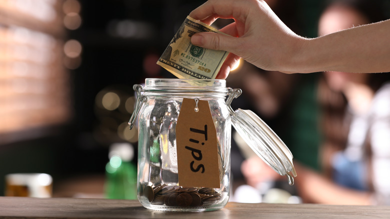 hand placing cash into jar