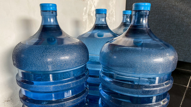 Three blue 5-gallon water jugs sitting on the floor