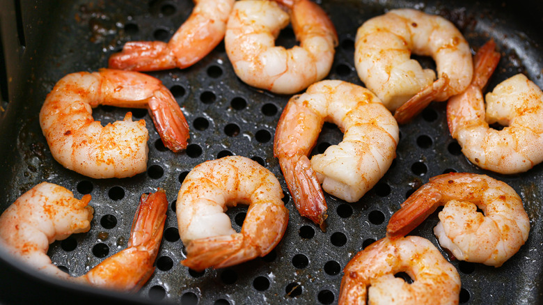 Cooked shrimp spread out in air fryer basket