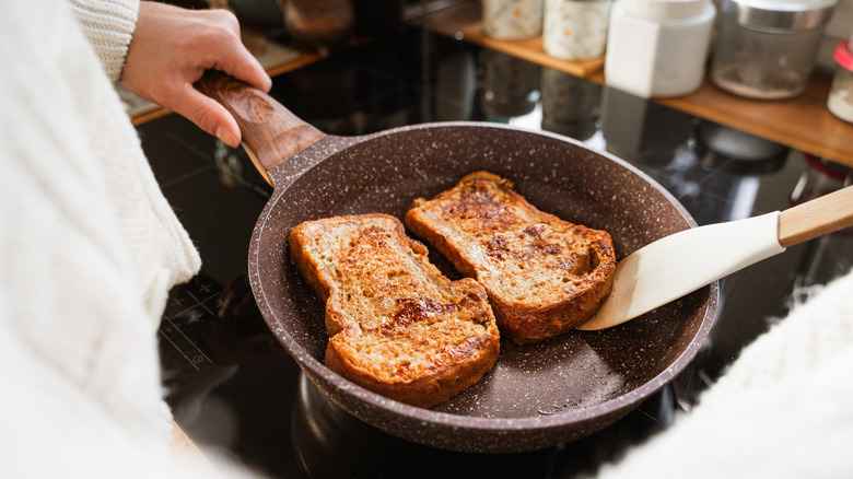 flipping french toast with a spatula in a pan