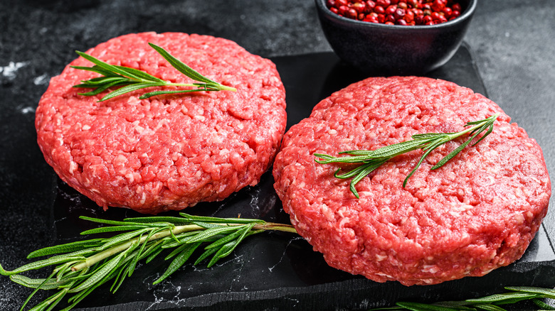 Two raw beef patties sprinkled with garnish