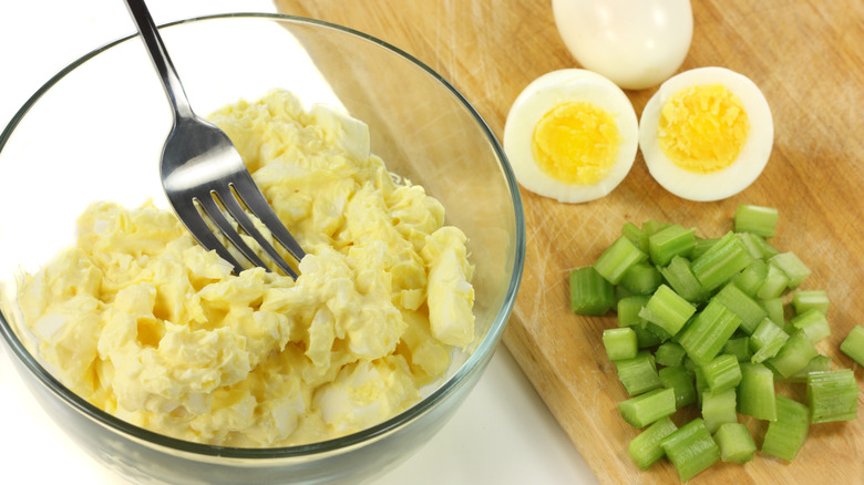 Egg salad in bowl with eggs and celery on side