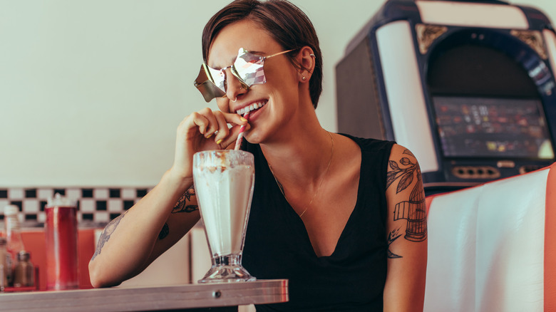 woman drinking milkshake at diner