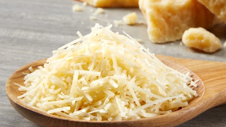 A pile of shredded Parmigiano Reggiano on a wooden spoon