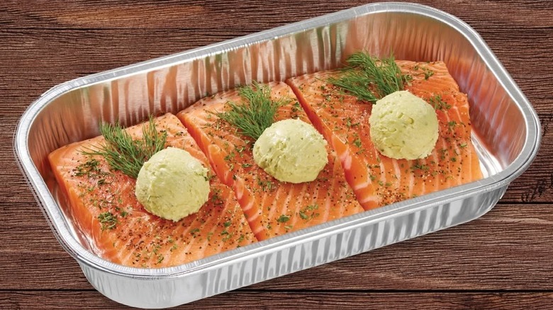 An aluminum baking tray containing three large pieces of Kirkland Signature Salmon Milano with Basil Pesto Butter