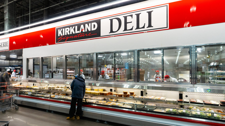 person searching through prepared food items at the Costco deli