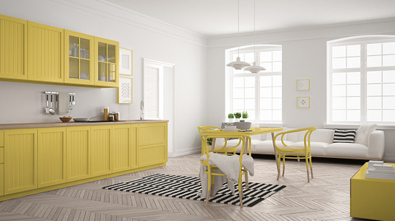 A kitchen with yellow cabinets, table, and chairs