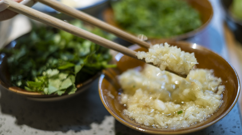 Chinese food bowl of chopped garlic with chopsticks picking some up