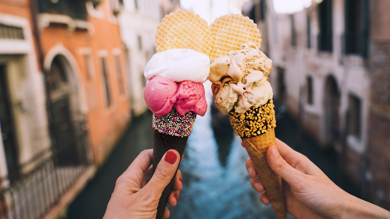 People holding ice cream cones in front of Venice canal