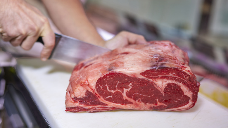 Person cutting slab of beef.