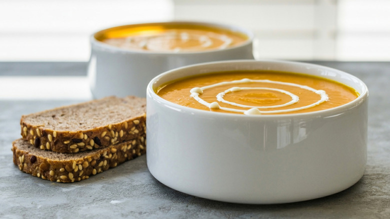 side view of bowl of butternut squash soup with swirl of coconut milk