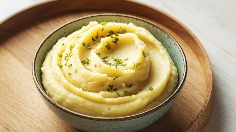 Bowl of herby mashed potatoes on a wood surface