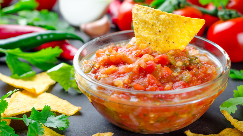 tomato salsa with chip in glass bowl