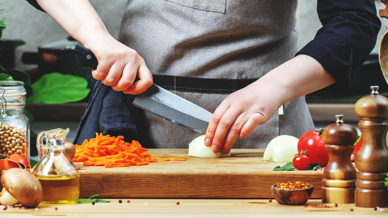 Person slicing an onion with a santoku knife