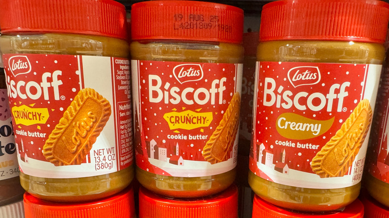 Jars of Biscoff crunchy and creamy cookie butter with red lids on a store shelf.