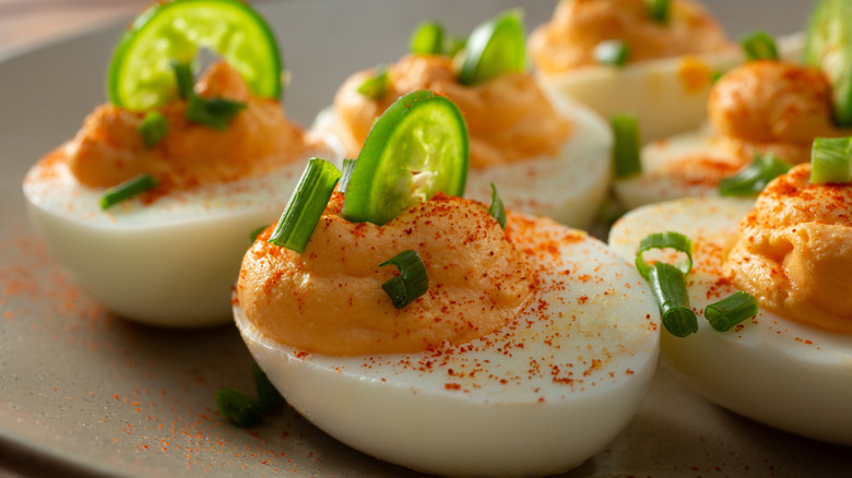 Deviled eggs with spices on top and small slice of jalapeno.