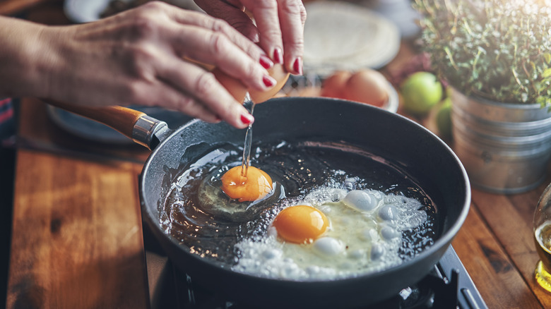 cracking eggs into cast iron skillet