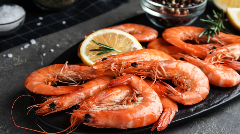 cooked shrimp with herbs on black plate
