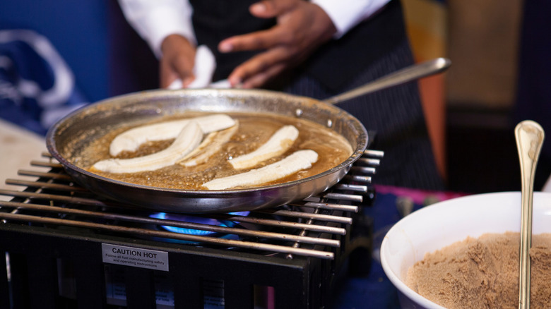 A close up of a chef flambéing bananas foster in a pan