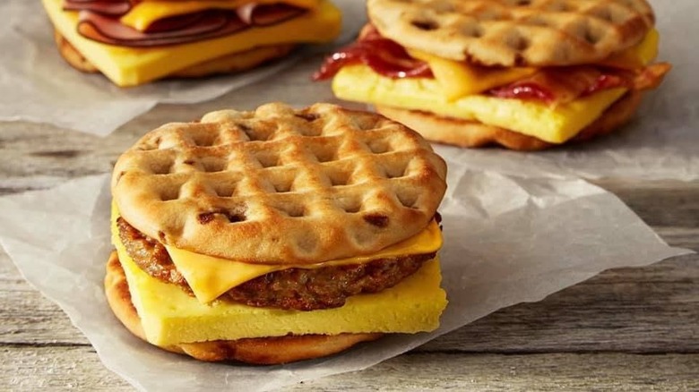 three Burger King waffle breakfast sandwiches sitting a table